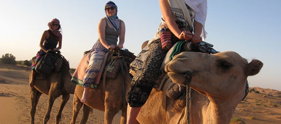 Visitors in Morocco riding camels in Merzouga